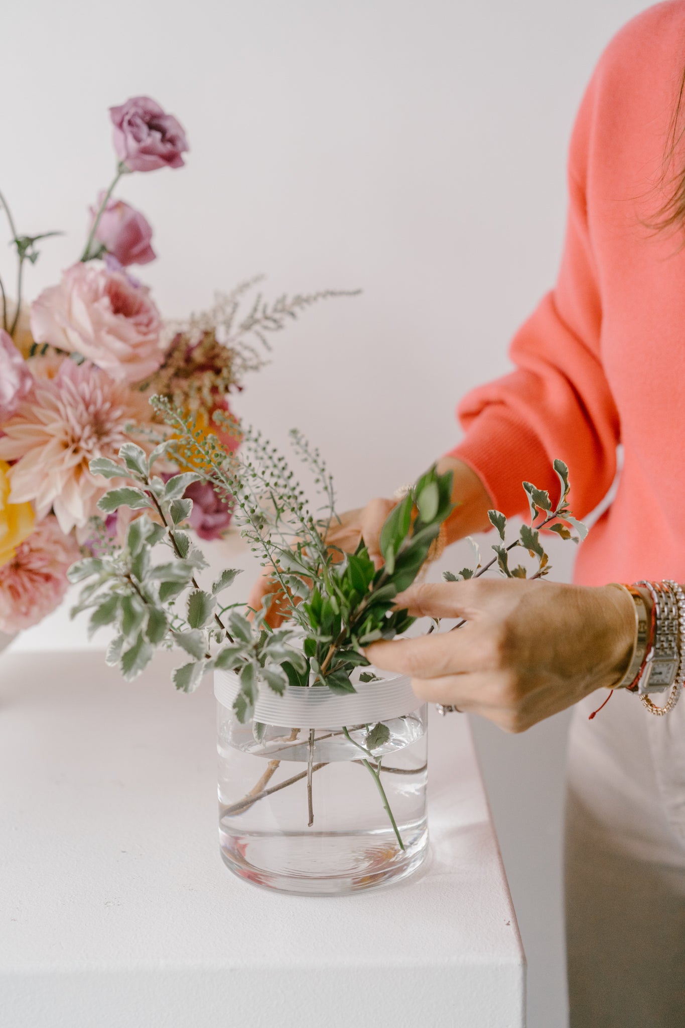 Person arranging flowers using the Blossom Grid tool in a clear round vase.