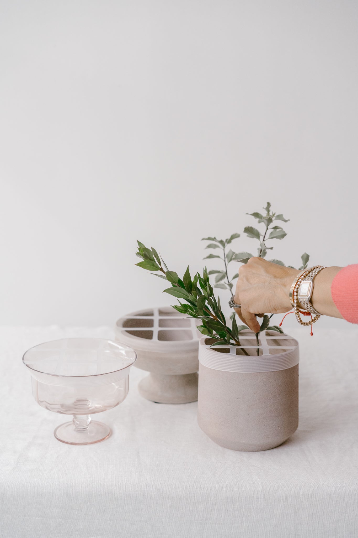 Person arranging a plant using the blossom grid tool in a gray pot.