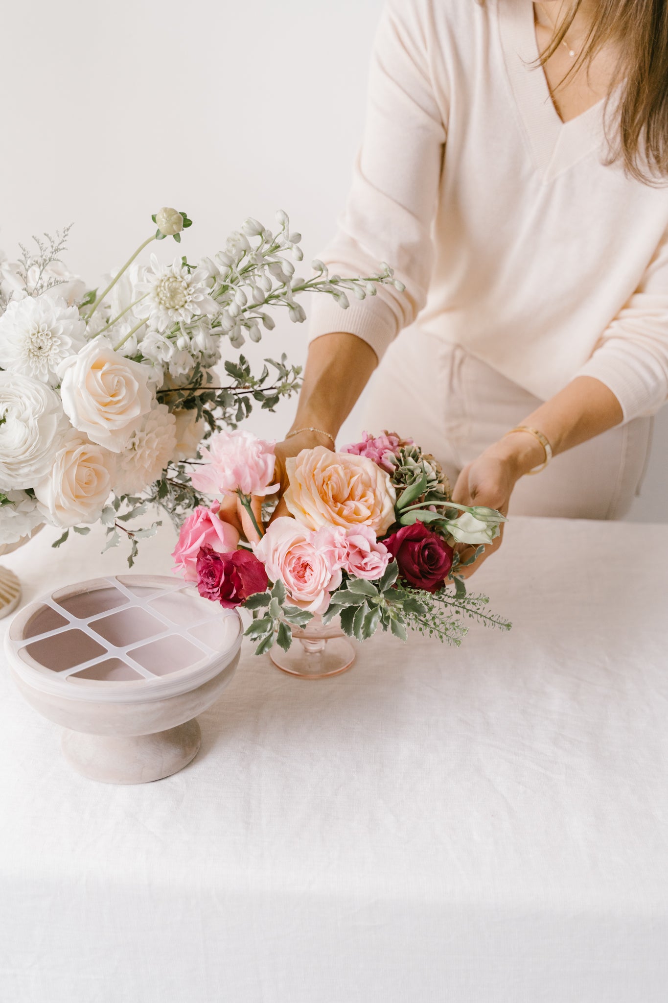 Person arranging flowers on a white surface using the blossom grid tool.