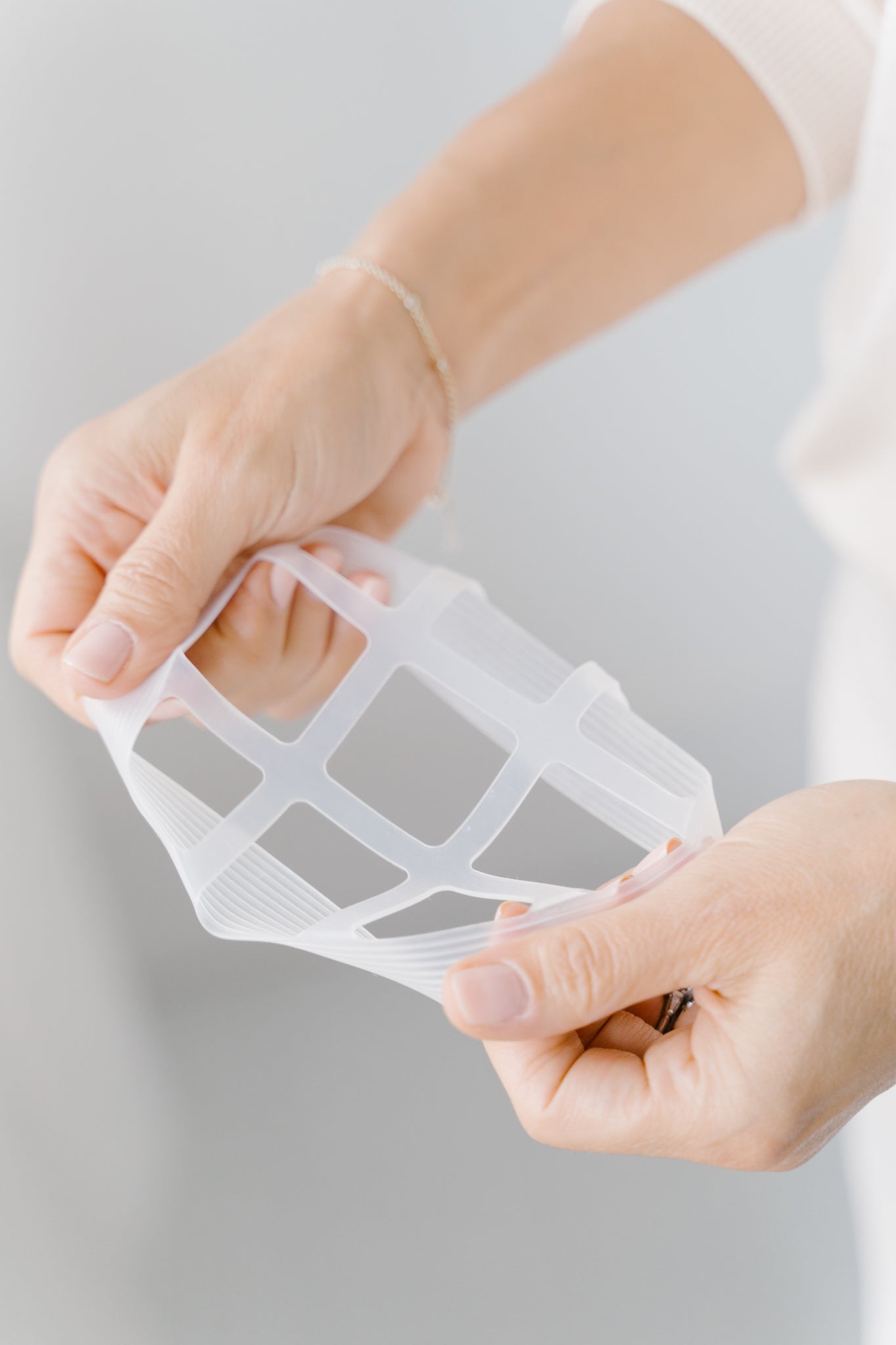 Person holding the blossom grid tool to show that it is a bit stretchy and dishwasher safe.