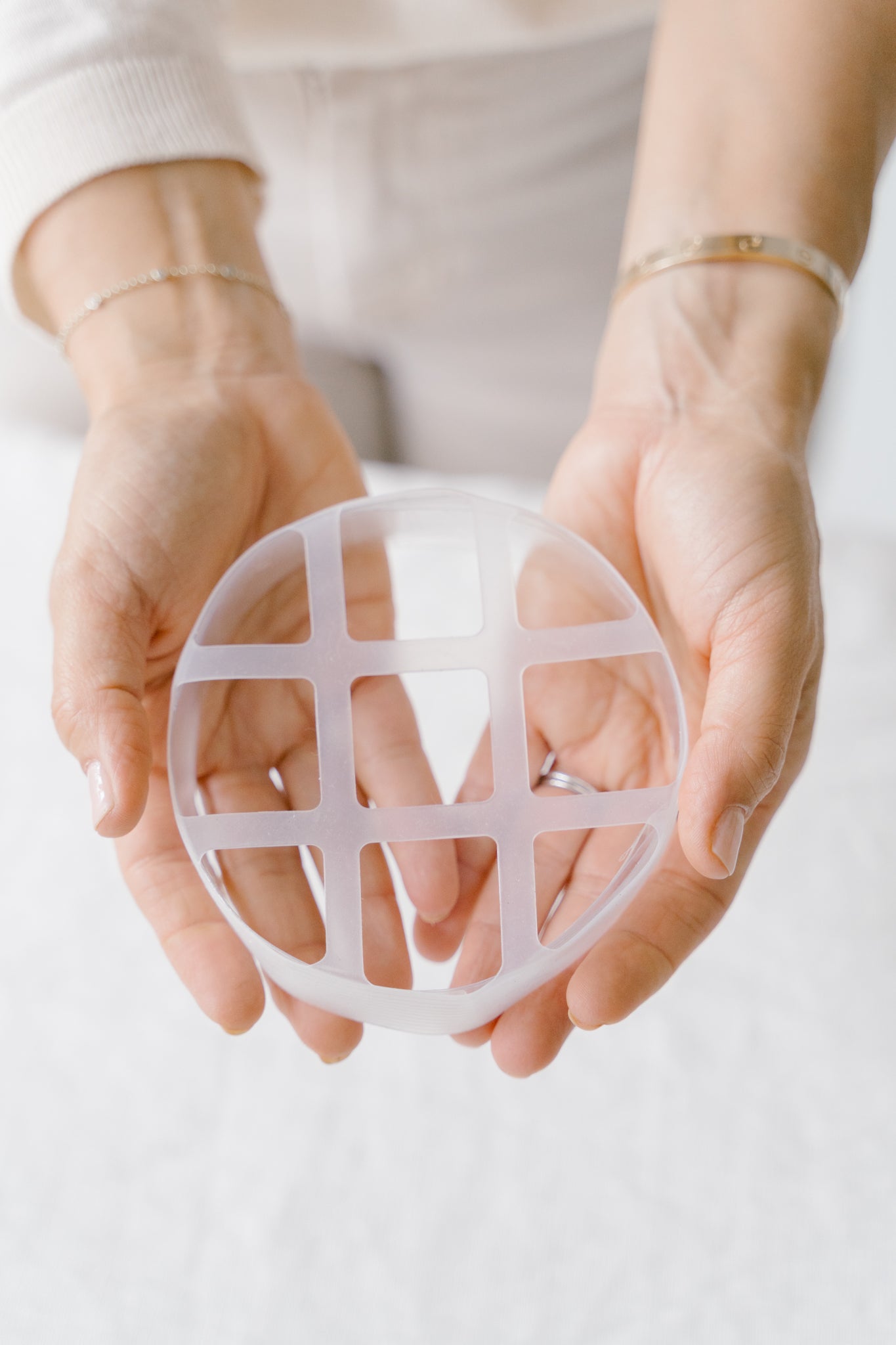 Hands holding a Blossom Grid with grid pattern on a white background